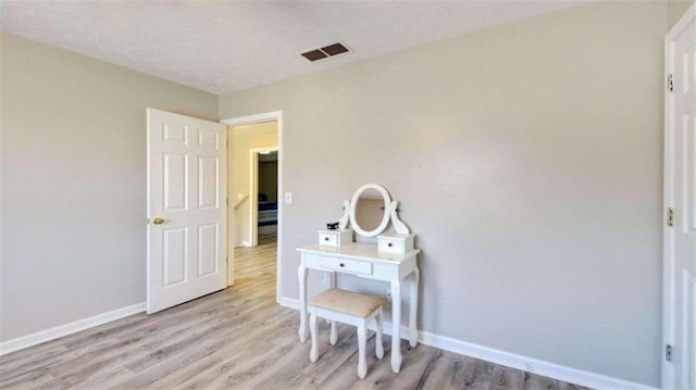 bedroom with a textured ceiling and light hardwood / wood-style floors