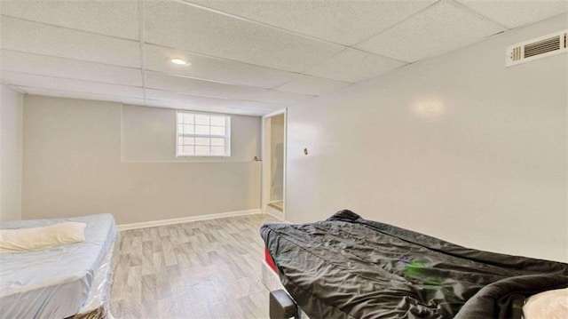 bedroom with hardwood / wood-style floors and a paneled ceiling