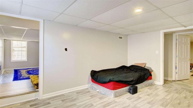 bedroom featuring light hardwood / wood-style flooring and a drop ceiling