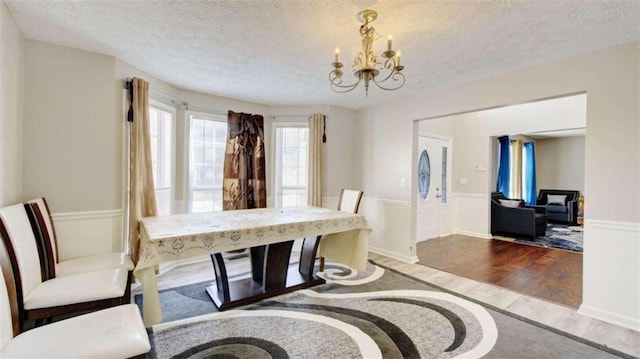 dining space with a textured ceiling, dark hardwood / wood-style flooring, and an inviting chandelier