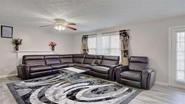 living room with ceiling fan, a textured ceiling, and light hardwood / wood-style flooring