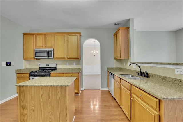kitchen featuring light stone counters, appliances with stainless steel finishes, a sink, light wood-type flooring, and visible vents