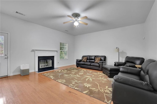 living area with ceiling fan, visible vents, wood finished floors, baseboards, and a glass covered fireplace