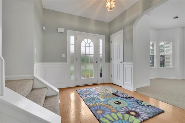 entryway featuring visible vents, arched walkways, wood finished floors, and a wainscoted wall