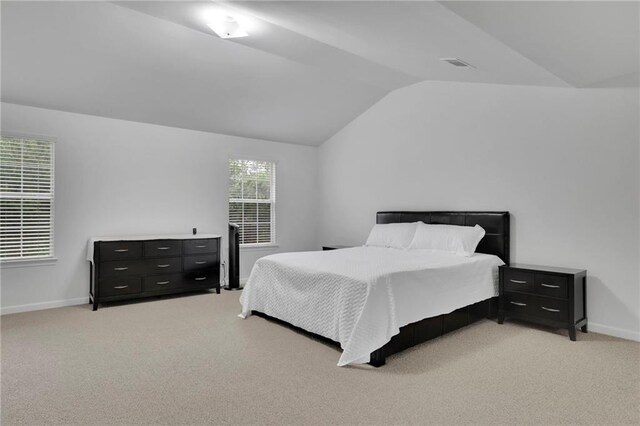bedroom with visible vents, baseboards, light colored carpet, and lofted ceiling