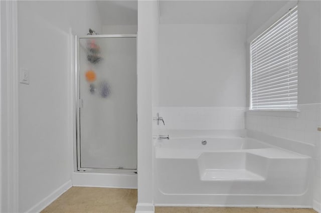 bathroom featuring plenty of natural light, a stall shower, and a garden tub