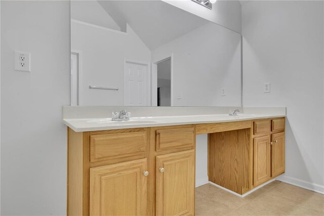 bathroom featuring double vanity, a sink, baseboards, and vaulted ceiling