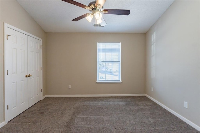 unfurnished bedroom featuring dark colored carpet, ceiling fan, and a closet