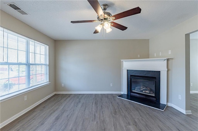 unfurnished living room featuring hardwood / wood-style flooring, ceiling fan, and a textured ceiling