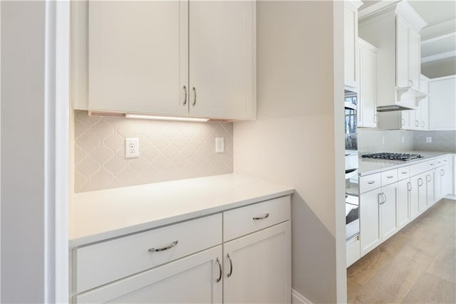 kitchen with white cabinetry, light hardwood / wood-style floors, stainless steel gas cooktop, and backsplash