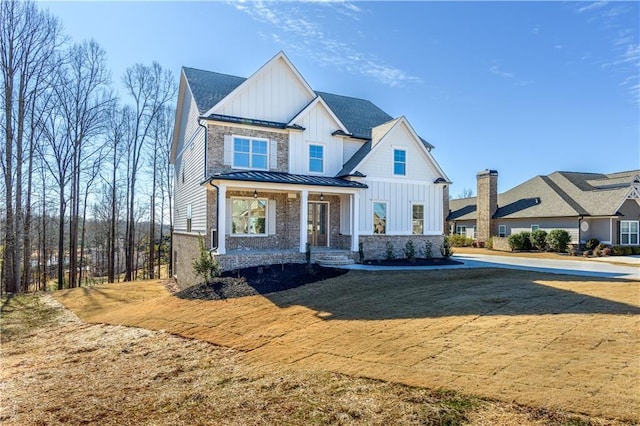 modern farmhouse style home featuring covered porch and a front lawn