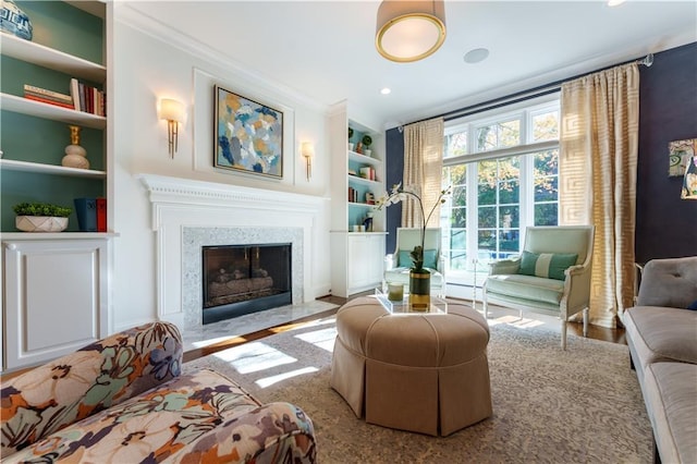 living area featuring a high end fireplace, built in features, recessed lighting, and crown molding