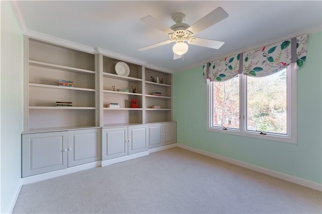 empty room featuring ornamental molding, a ceiling fan, baseboards, and light carpet