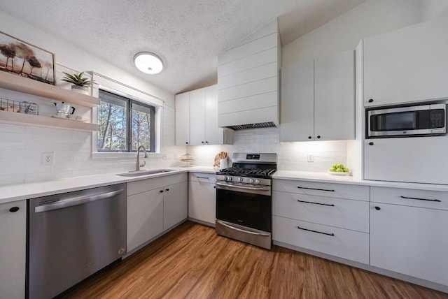 kitchen with stainless steel appliances, a sink, light countertops, and light wood-style floors