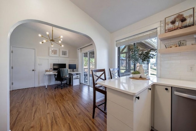 interior space featuring arched walkways, a decorative wall, an inviting chandelier, vaulted ceiling, and wood finished floors