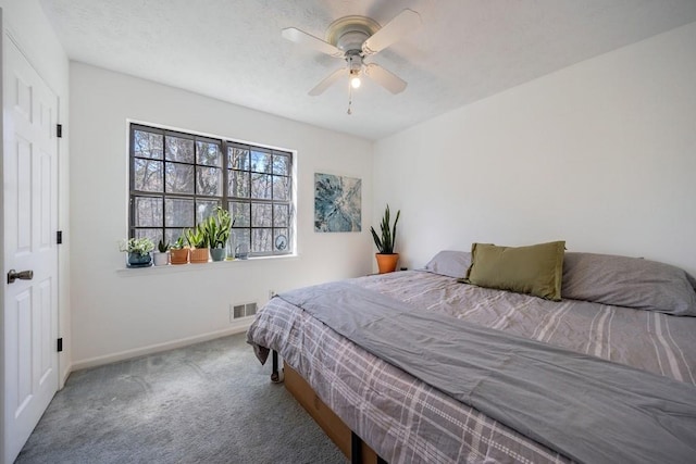 carpeted bedroom featuring a ceiling fan, visible vents, a textured ceiling, and baseboards