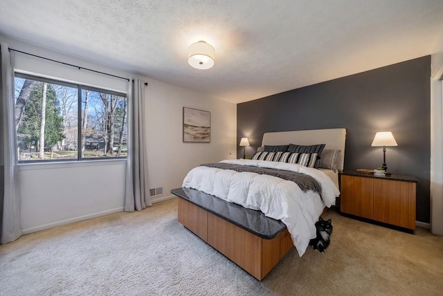 bedroom featuring baseboards, a textured ceiling, visible vents, and light colored carpet