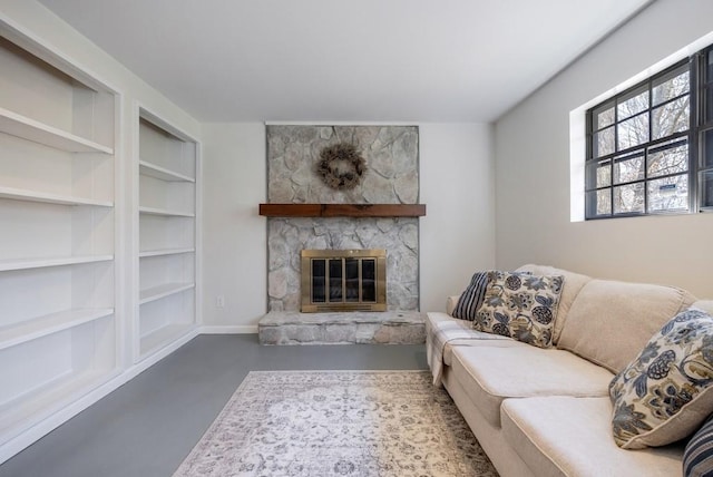 living room featuring baseboards, concrete floors, a fireplace, and built in features