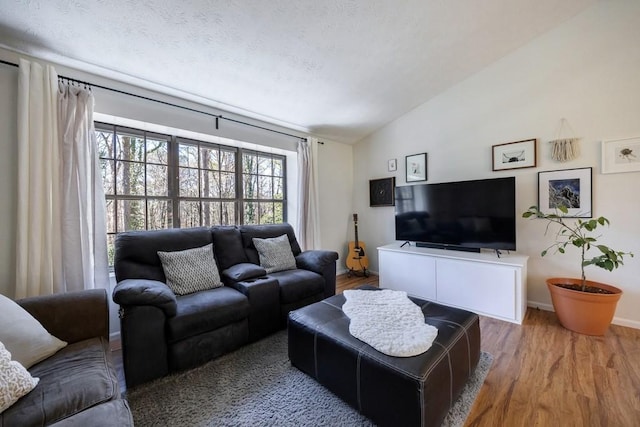 living room featuring a textured ceiling, baseboards, vaulted ceiling, and wood finished floors