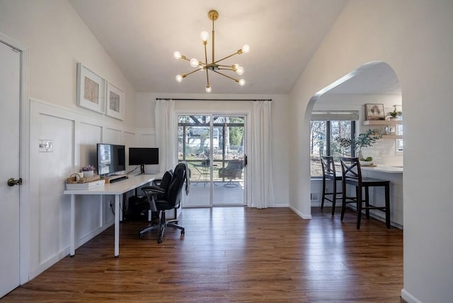 office area featuring lofted ceiling, a decorative wall, arched walkways, and wood finished floors