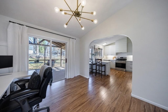 home office featuring arched walkways, a notable chandelier, lofted ceiling, a sink, and wood finished floors