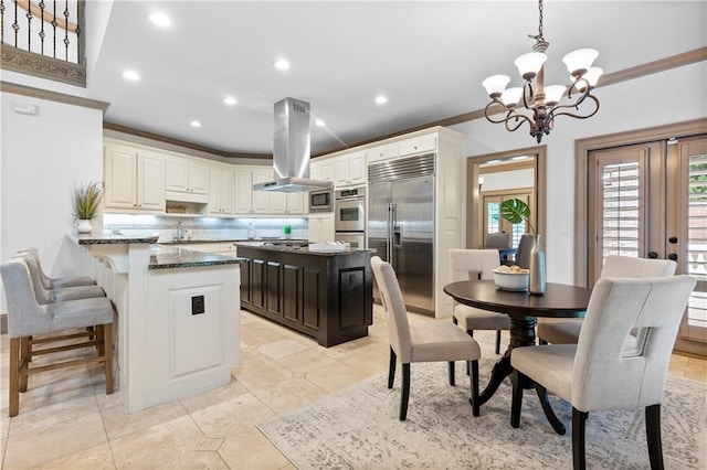 8370 Royal Melbourne Way, Duluth, GA 30097 - kitchen with appliances with stainless steel finishes, island range hood, decorative backsplash, a chandelier, and dark stone countertops