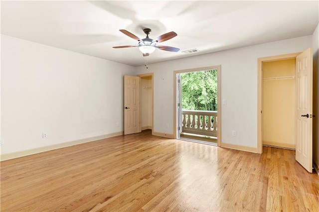 8370 Royal Melbourne Way, Duluth, GA 30097 - unfurnished bedroom with a walk in closet, access to outside, light wood finished floors, a ceiling fan, and a closet