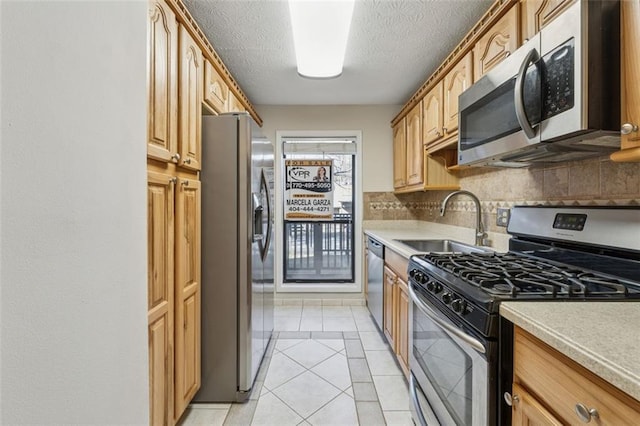 kitchen with stainless steel appliances, light countertops, a sink, and decorative backsplash