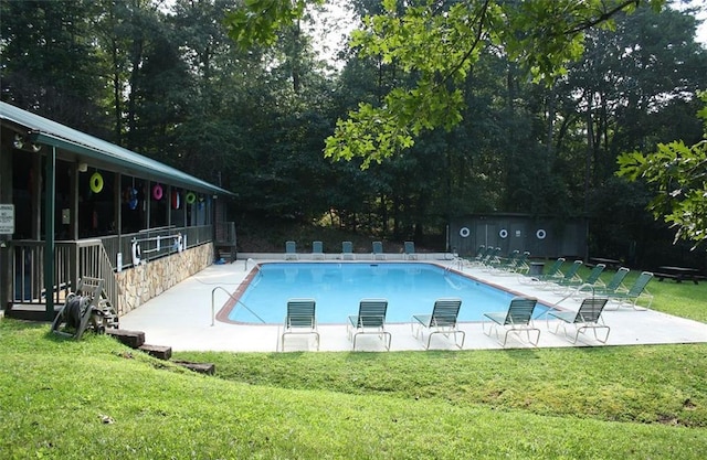 pool with a patio area and a lawn