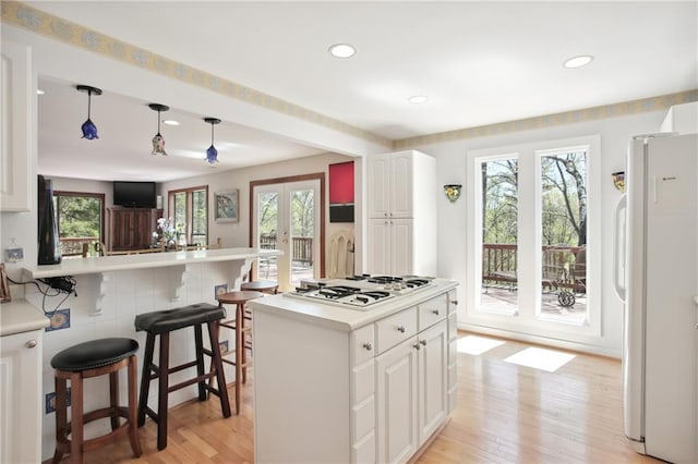 8145 Stone Hill Rd, Cumming, GA 30028 - kitchen with white appliances, light wood-style floors, recessed lighting, a kitchen breakfast bar, and white cabinetry