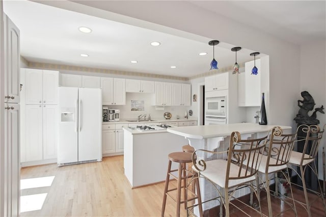 8145 Stone Hill Rd, Cumming, GA 30028 - kitchen featuring white appliances, a sink, a breakfast bar area, a peninsula, and light wood-type flooring