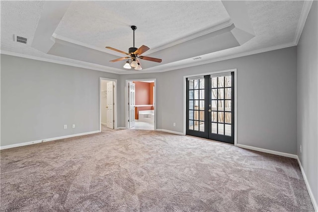 unfurnished room with a raised ceiling, ceiling fan, french doors, and crown molding