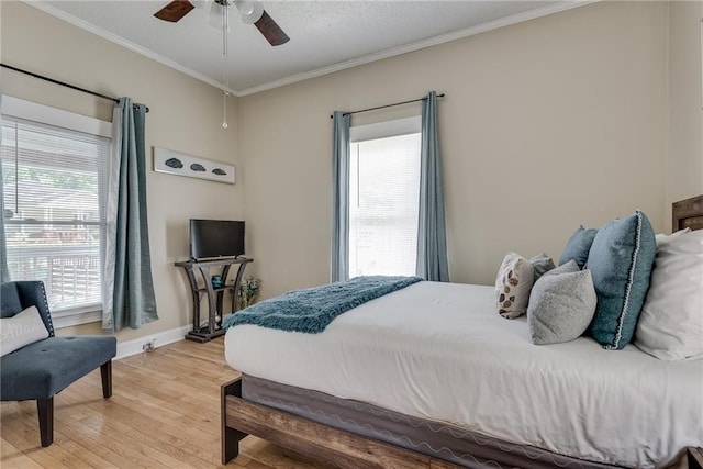 bedroom featuring baseboards, a ceiling fan, crown molding, and light wood-style floors