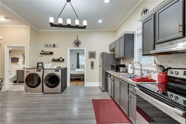 kitchen featuring independent washer and dryer, light wood-style flooring, a sink, stainless steel electric stove, and crown molding