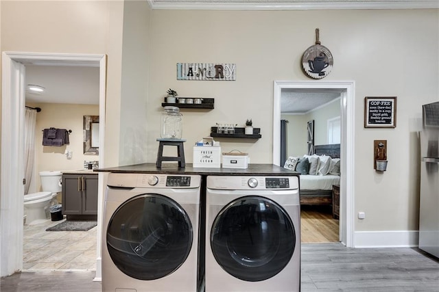 clothes washing area featuring crown molding, baseboards, laundry area, light wood-style flooring, and separate washer and dryer