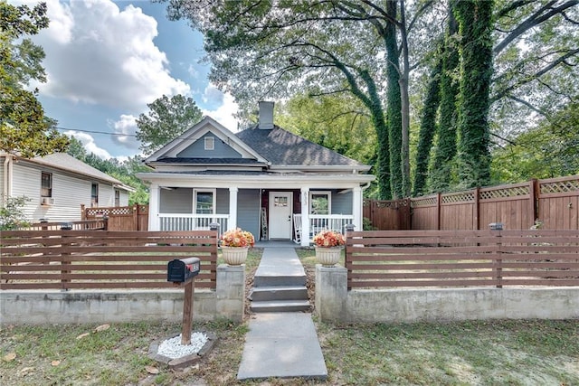 view of front of property with a chimney, a porch, fence private yard, and roof with shingles