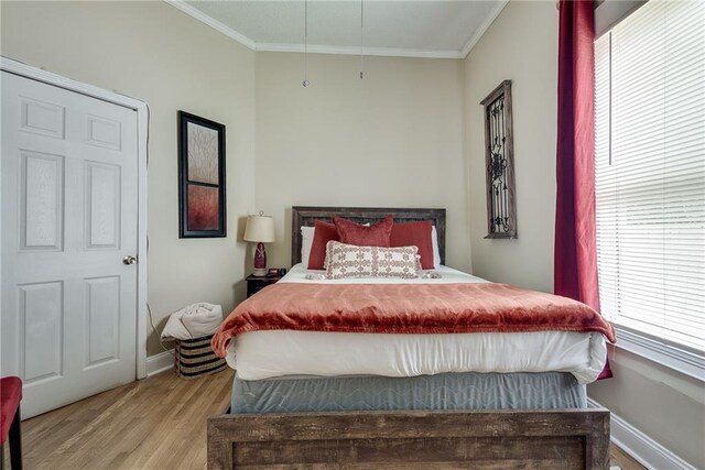 bedroom featuring baseboards, light wood-style flooring, and crown molding