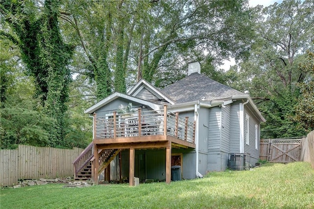 back of house featuring a lawn, central AC, fence, a shingled roof, and stairs