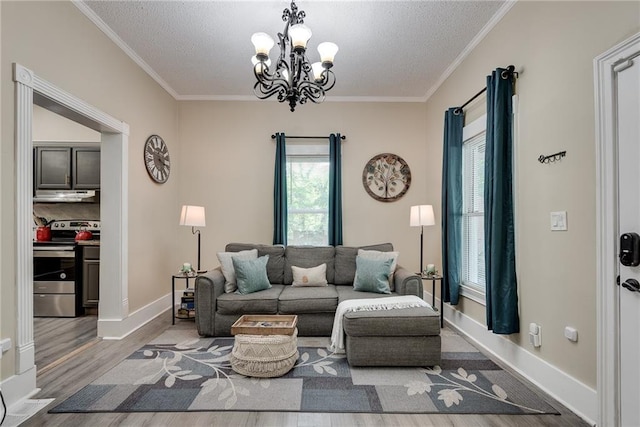 living room with a textured ceiling, crown molding, baseboards, and wood finished floors