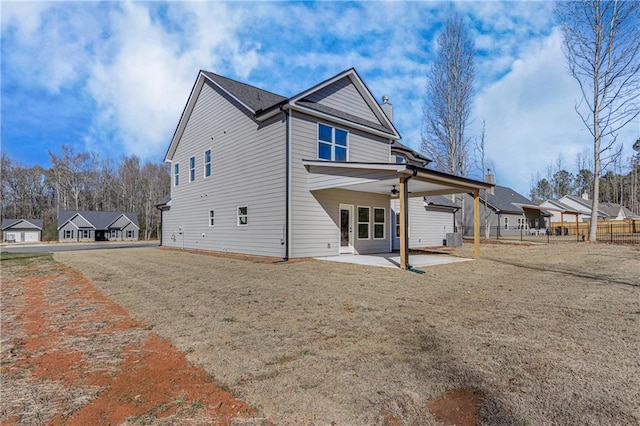 rear view of property featuring a yard, a patio area, fence, and a chimney