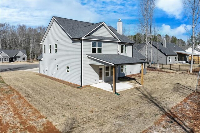 rear view of house with a patio, cooling unit, fence, roof with shingles, and a chimney