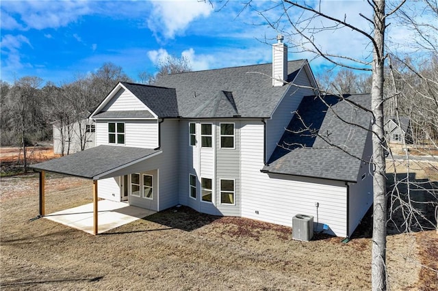 back of house featuring a patio area, a chimney, central AC, and roof with shingles