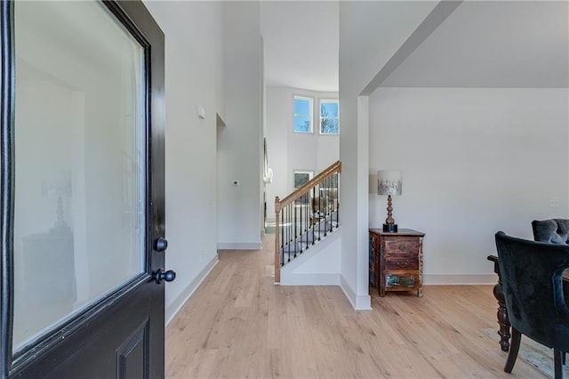 entrance foyer featuring light wood-style flooring, stairs, and baseboards