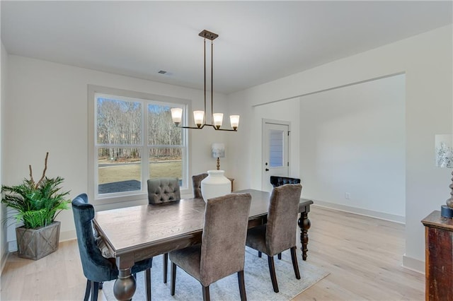 dining room with light wood finished floors, baseboards, and an inviting chandelier