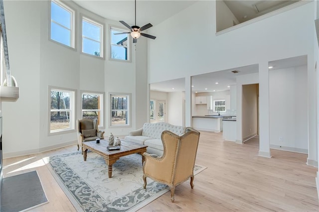 living area with light wood-type flooring, plenty of natural light, and baseboards