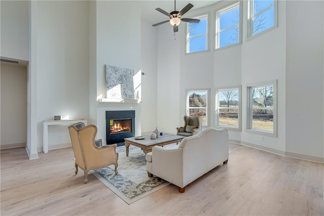 living area featuring a wealth of natural light, wood finished floors, and a warm lit fireplace