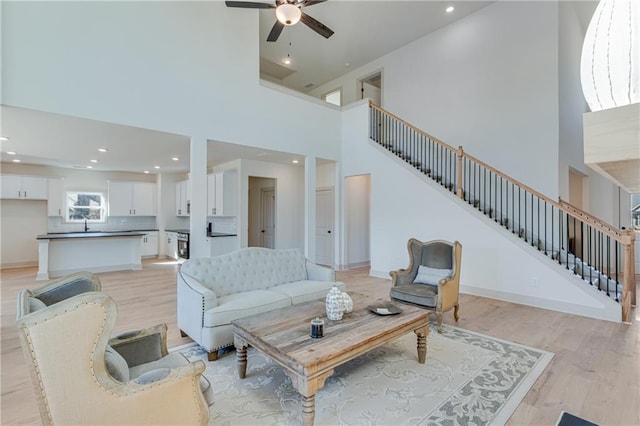 living room featuring stairway, light wood-style flooring, and baseboards