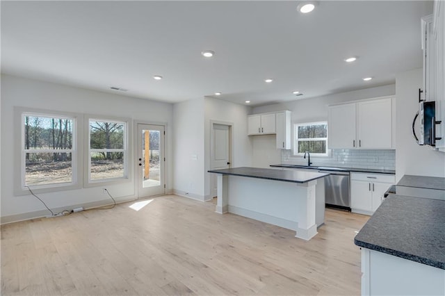 kitchen featuring backsplash, dark countertops, appliances with stainless steel finishes, and light wood finished floors