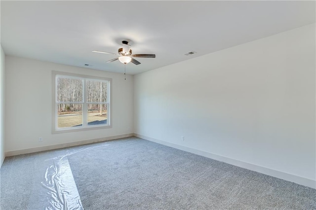 spare room with ceiling fan, light colored carpet, visible vents, and baseboards