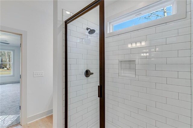 full bathroom with plenty of natural light, a stall shower, and baseboards